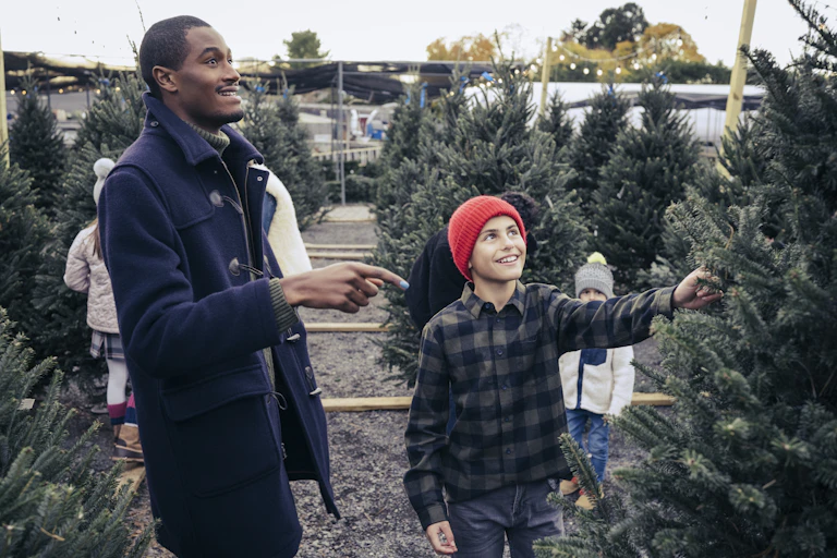 man and boy pointing to a pine tree on a retail lot