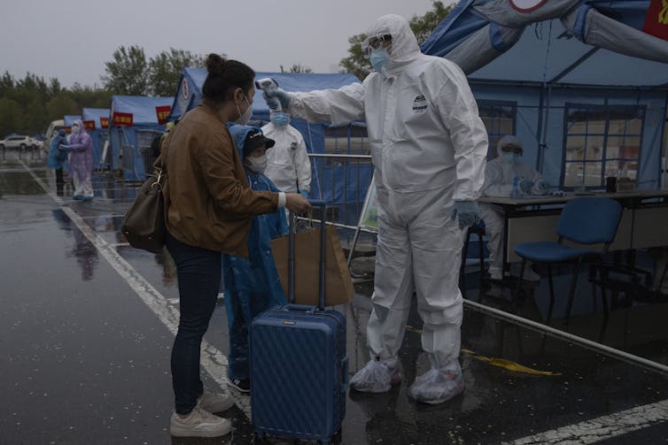 A health worker checking a traveller at a checkpoint.