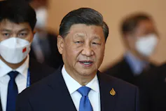 Chinese president Xi Jinping with people in masks behind him.