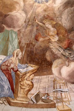 A faded illustration shows an angel looking down at a woman kneeling on the ground in a cloak, surrounded by rays of light.