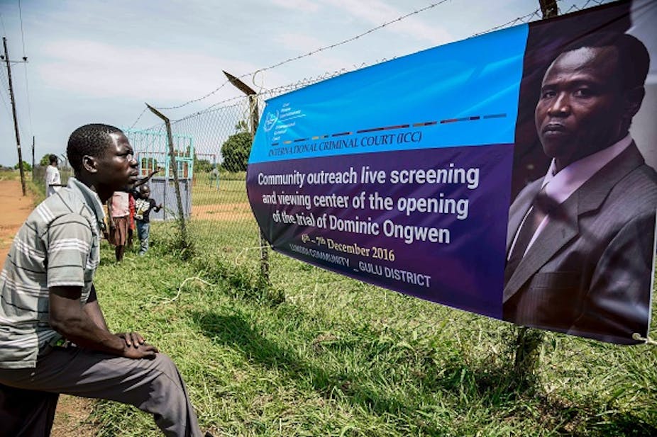 Man looks at a banner announcing screening of Dominic Ongwen's ICC proceedings