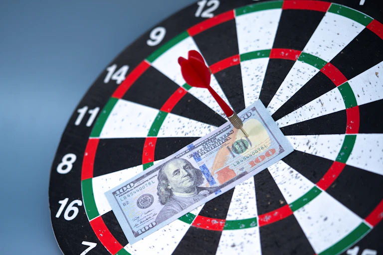 a $100 bill is stuck to a dartboard with a dart sticking in it