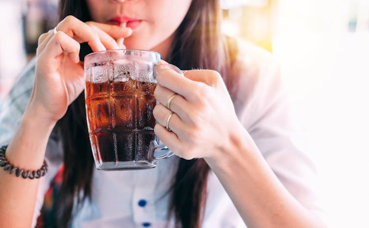 A woman drinks a cola.