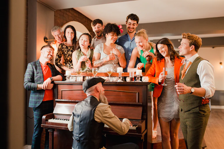 A crowd sings around a piano