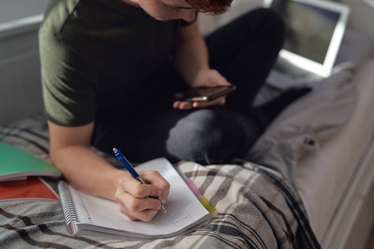 Young man on the phone with a notepad.