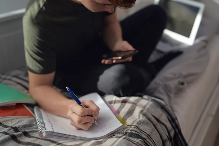 Young man on the phone with a notepad.