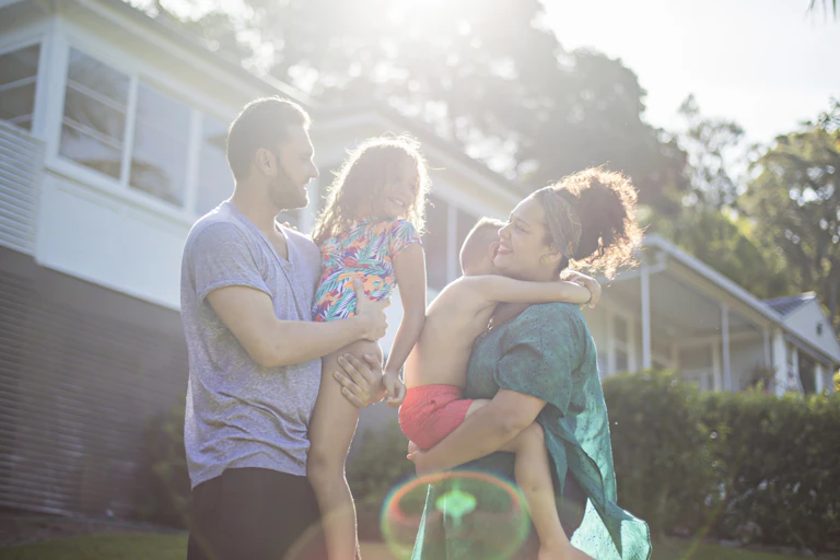 A First Nations family stand together outside in the sunlight.