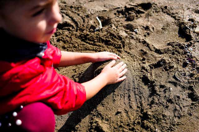 A young child plays with wet sand.
