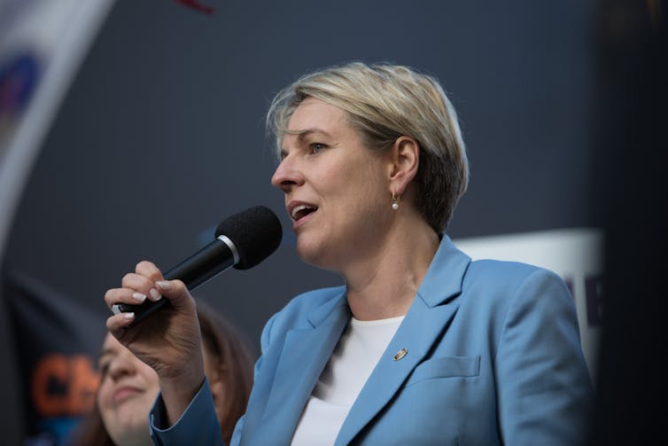 woman in blue jacket holds microphone