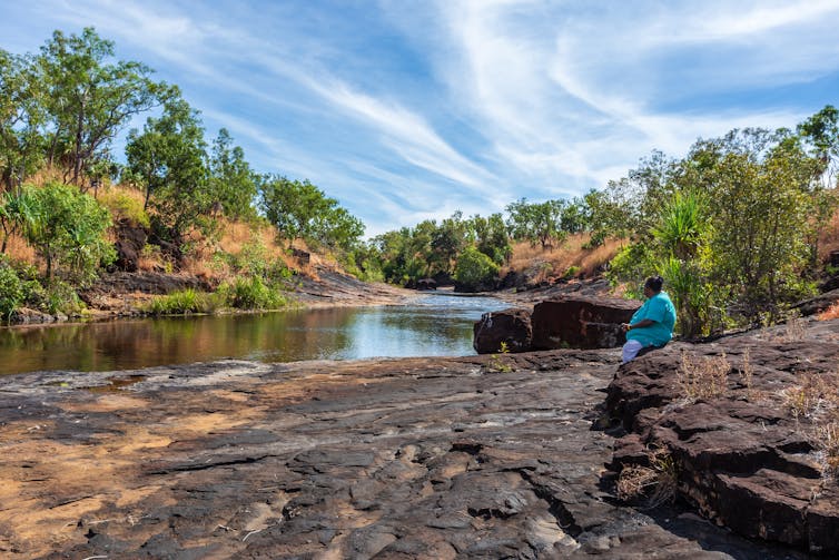 Indigenous woman sits by river