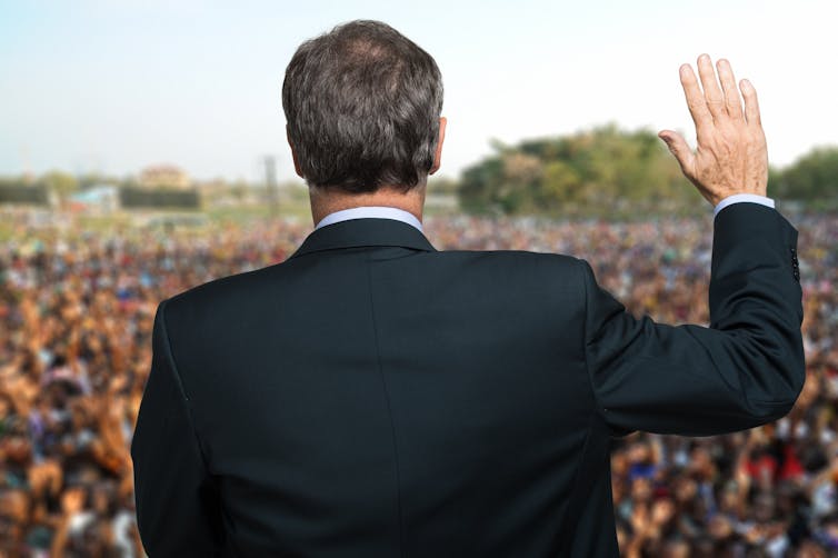 Politician talking and making an oath with his arm raised.