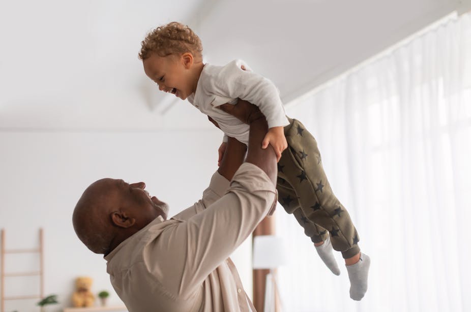 A grandfather lifts his grandchild into the air.