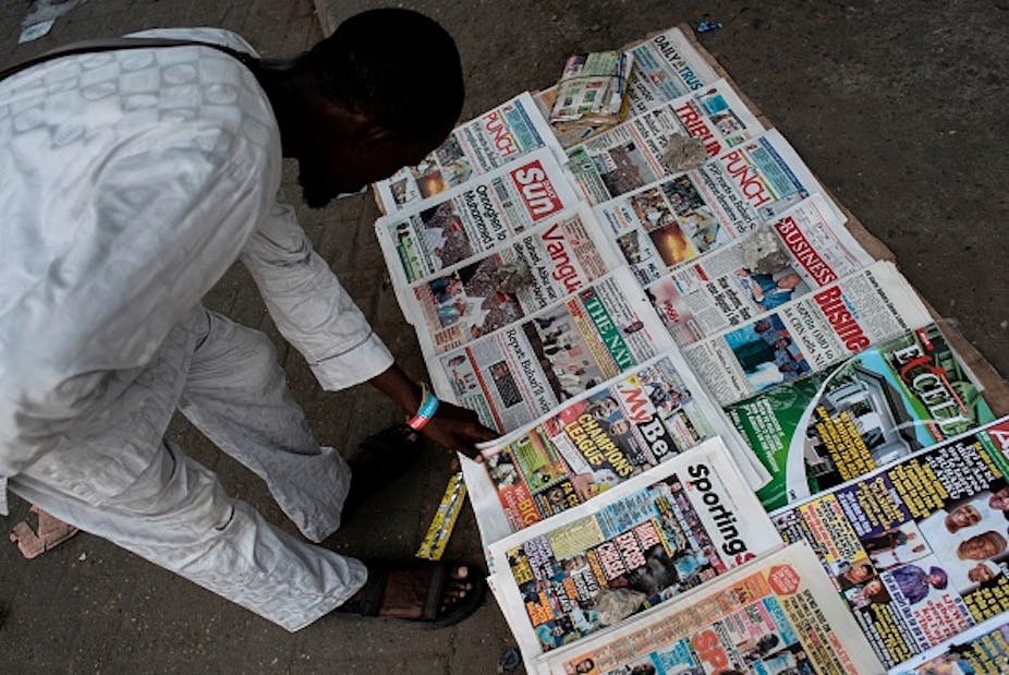 A man scans newspapers on sale at a makeshift street newstand on the ground in Nigeria.