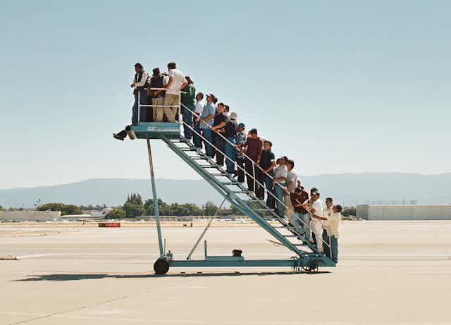 A plane staircase leading nowhere but full of people.