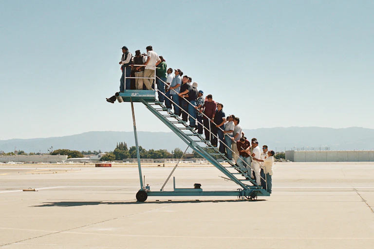 A plane staircase leading nowhere but full of people.