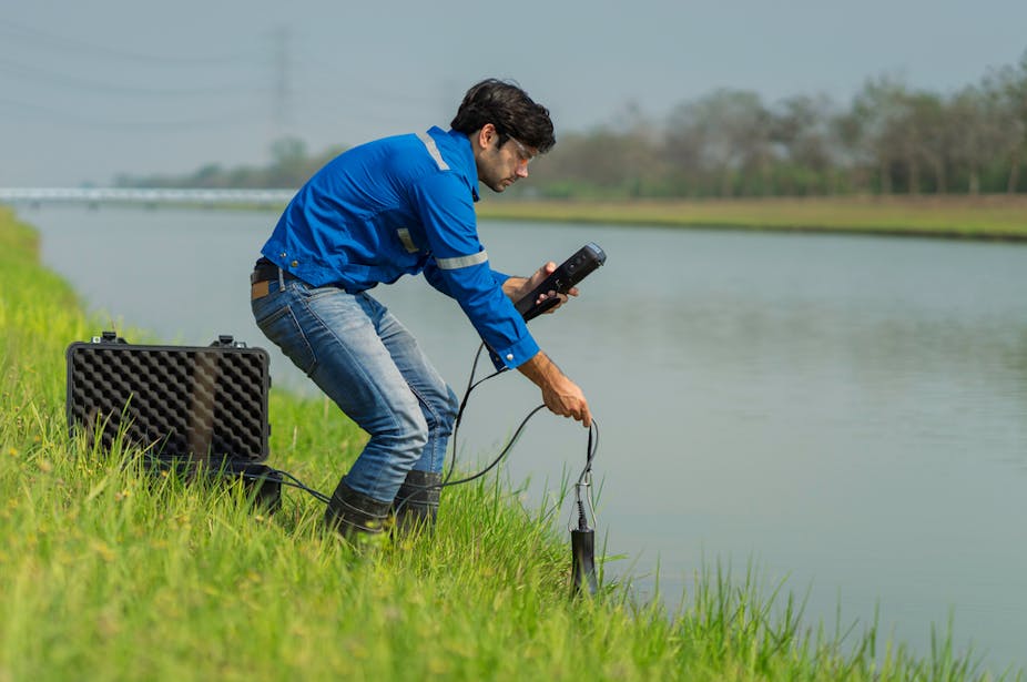 A men with specialist equipment testing the water quality of a canal.