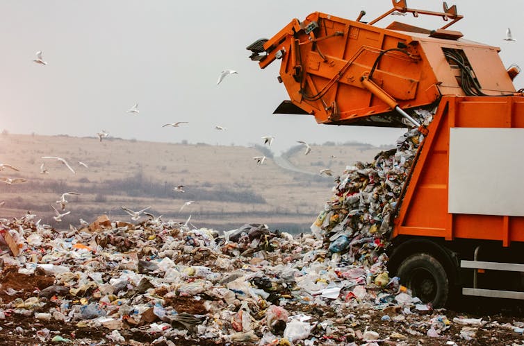 A garbage truck dumping waste on a landfill.
