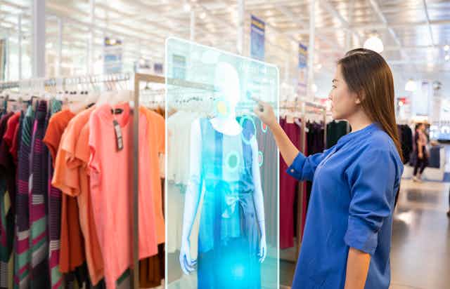 Woman uses touch screen in clothes store.