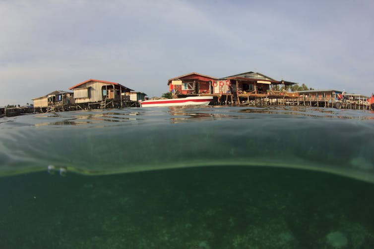 Wooden seaside lodges visible above ocean water.