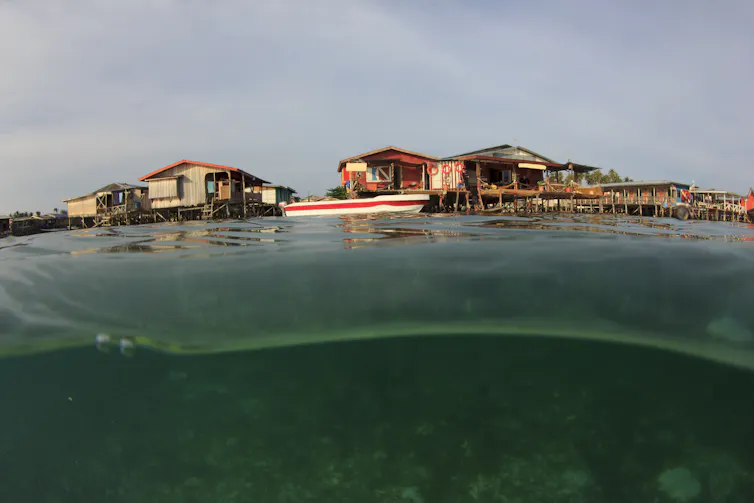 Wooden seaside lodges visible above ocean water.