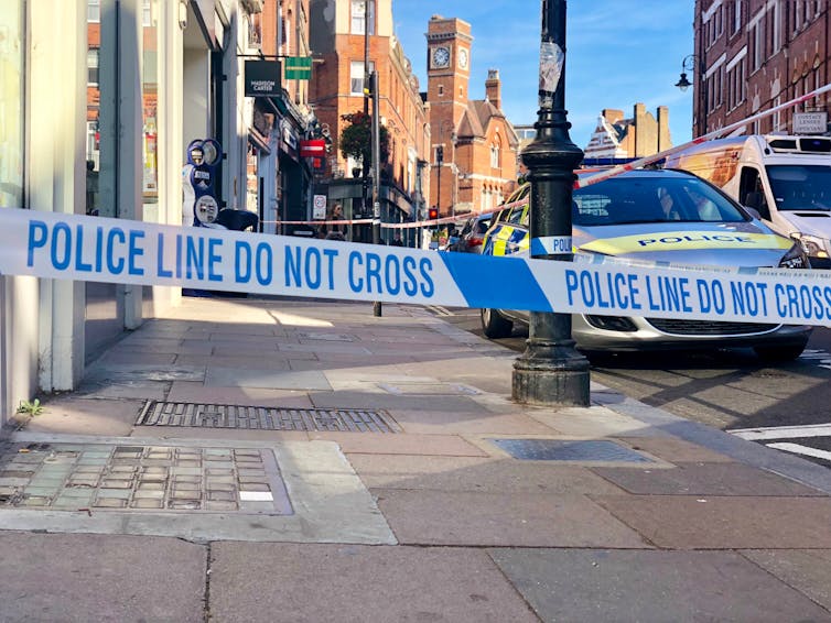 Police caution tape sectioning off an area of a street.