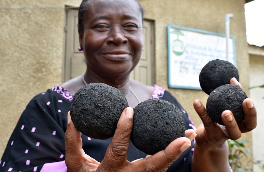 femme africaine qui tient des boules à base de charbon