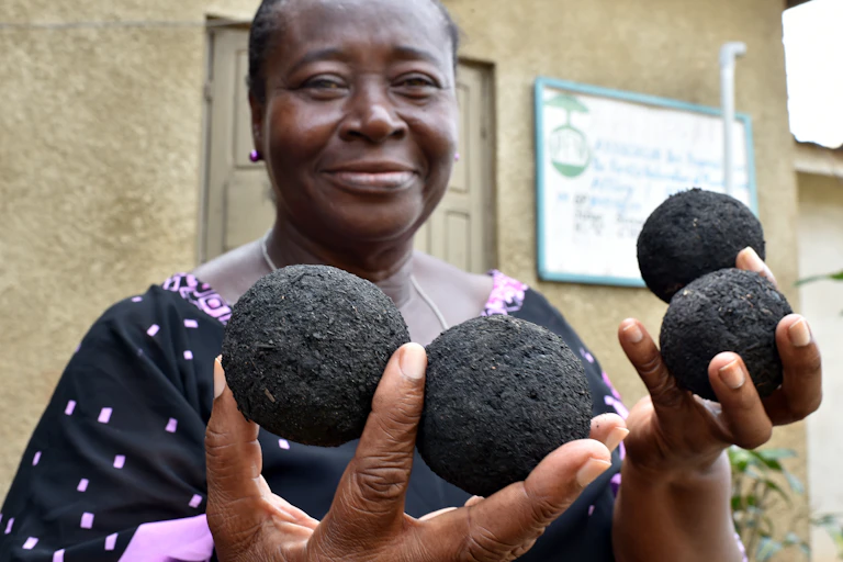 femme africaine qui tient des boules à base de charbon