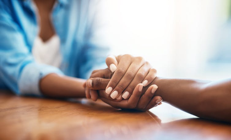 The hands of two people clasping over a table.