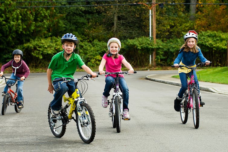 Little kids ride bikes.