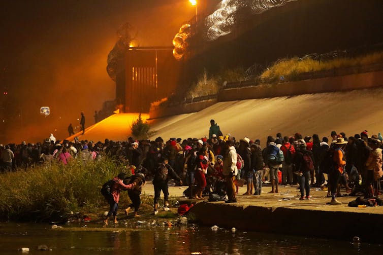 Thousands of people are lined up near a concrete barrier.