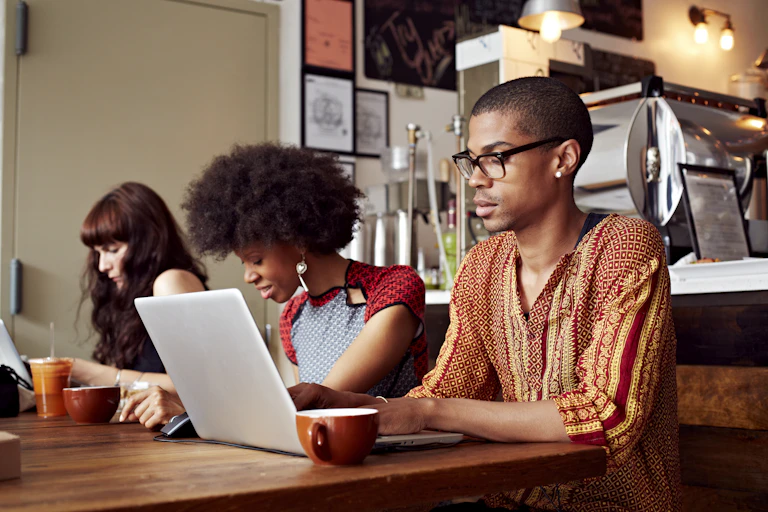 People working at laptops and smartphones in coffee shop