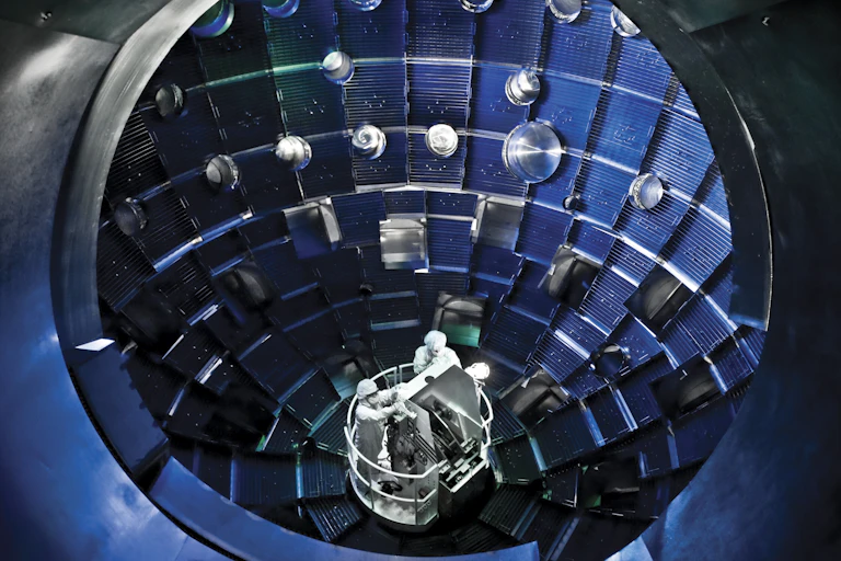Two people inside of a large metal sphere with holes on the inside.