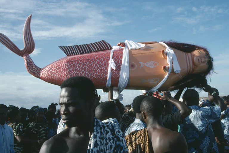 People hoist a coffin that resembles a mermaid.