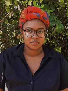 Woman wearing glasses and headscarf.