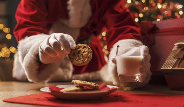gloved hands reach for cookies and milk