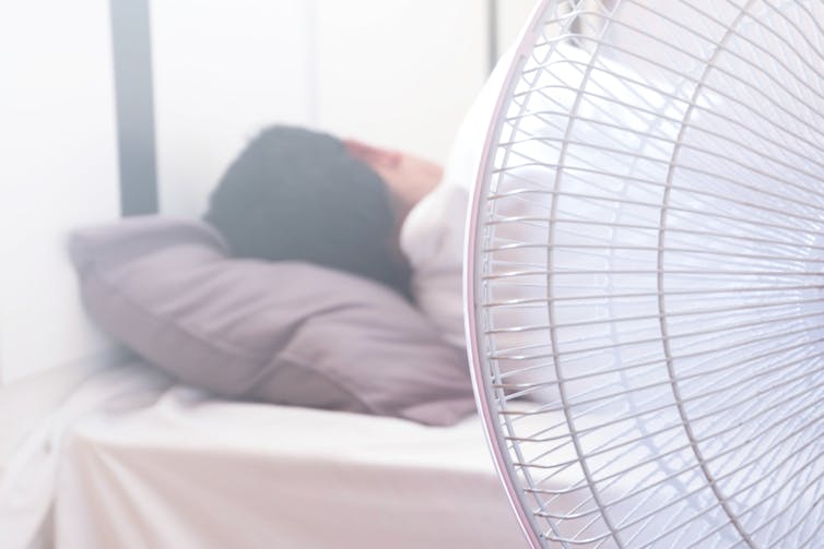 Fan next to someone asleep in bed