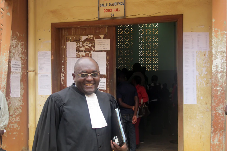 A man wearing a robe and standing in front of a courthouse.