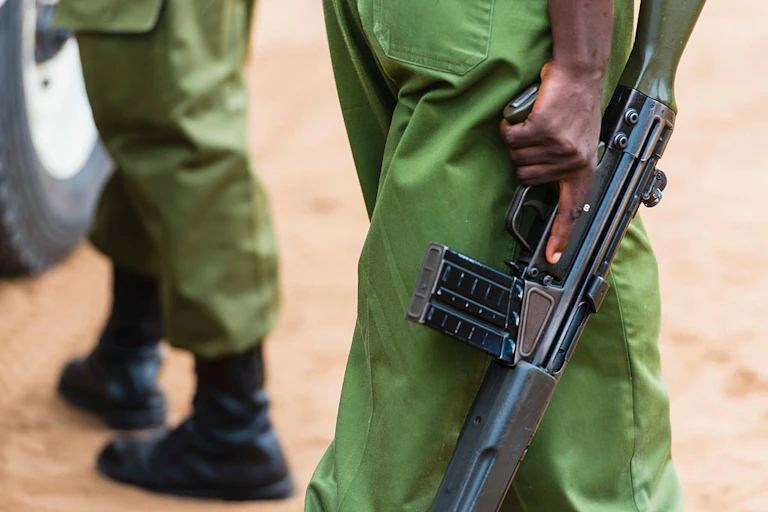 A shot of a man in green army trousers that is taken from the waist down, and he is holding a gun.