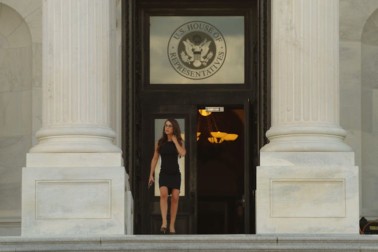 A woman in a black dress standing at the top of the House of Representatives steps.