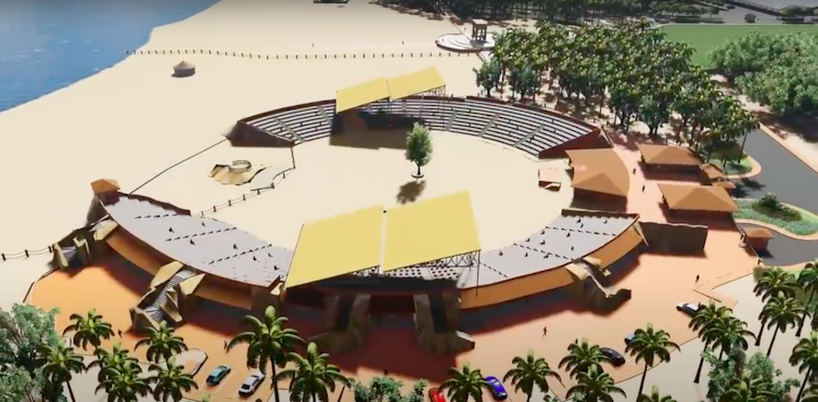A circular structure on the beach with a tree at its centre and seating all around it.  The arena for vodun performances at the Marina Project. Screenshot/YouTube/Presidency of Benin 