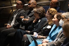 a picture of 5 people listening intently to 4 panelists