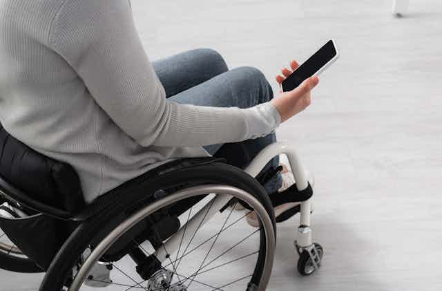 View from above of a woman in a wheelchair holding a mobile phone with a blank screen