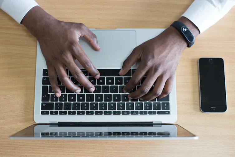 Two hands typing on a laptop.