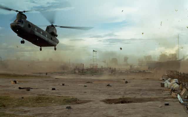 A US helicopter flying over an area of wasteland.