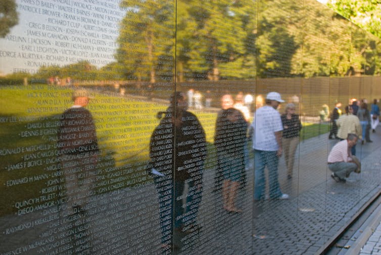 Reflections of people visiting the Vietnam memorial.