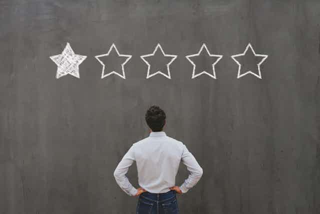 Man staring up at a one-star rating on a chalkboard