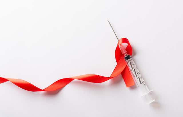 A red ribbon and a syringe on a white background