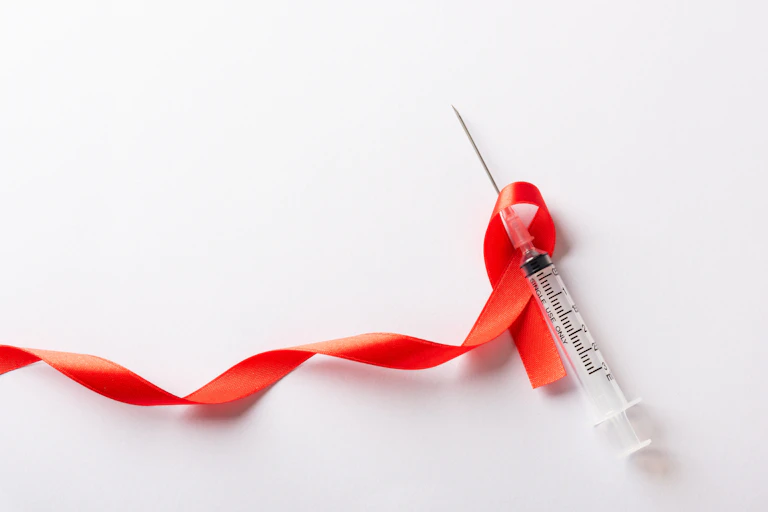 A red ribbon and a syringe on a white background