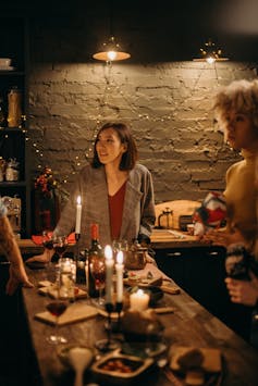 Women standing around a cande-lit table, drinking wine