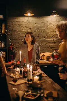 Women standing around a cande-lit table, drinking wine